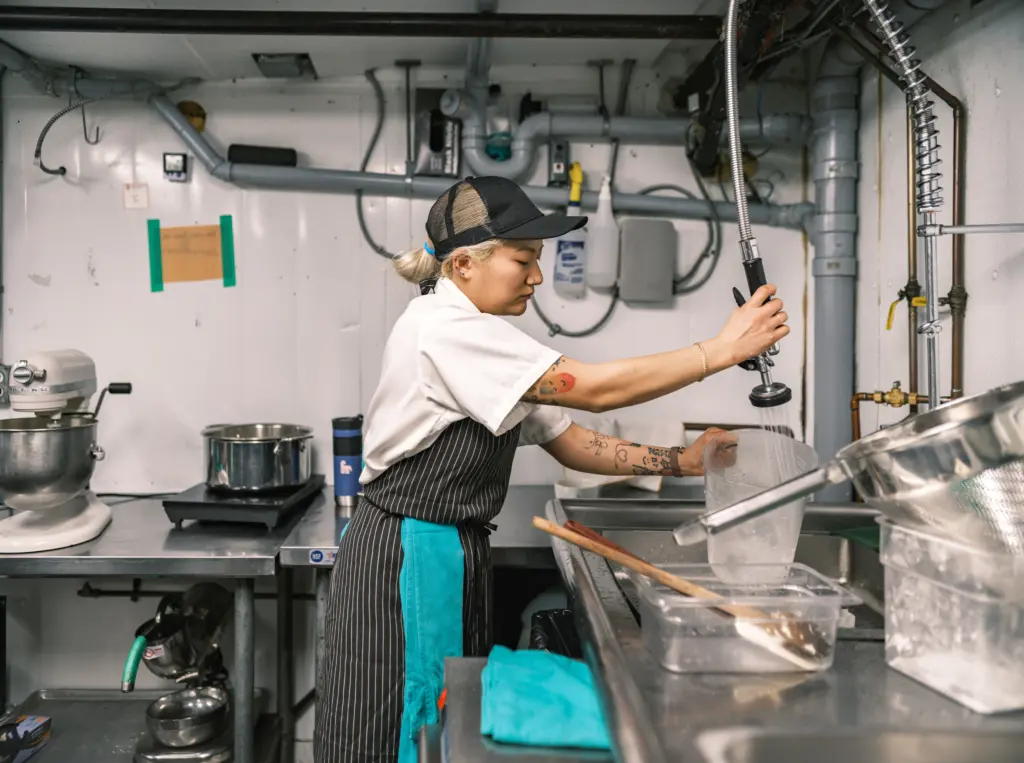 Young Korean female chef working in restaurant kitchen