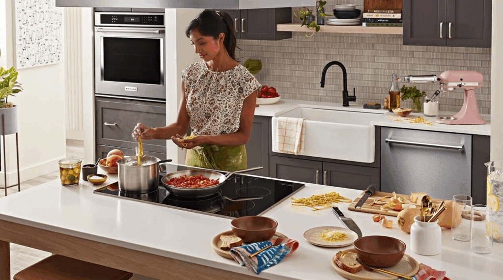 Woman cooking pasta and tomato sauce on a modern induction cooktop in a home kitchen.