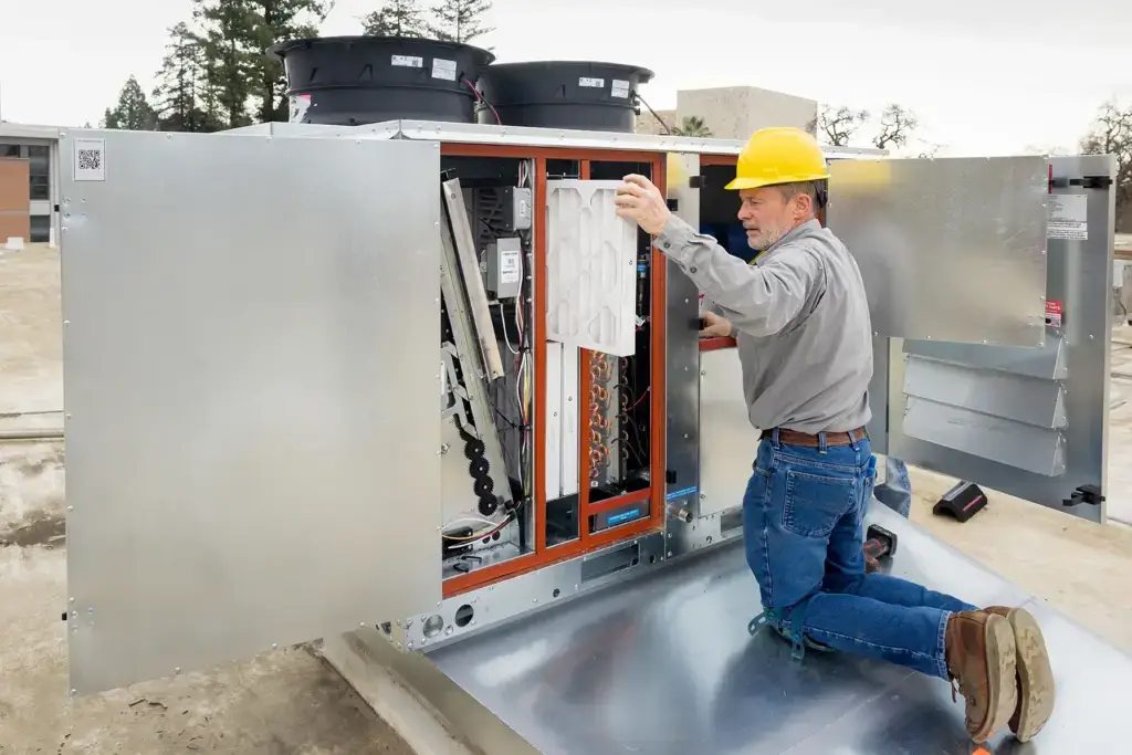 Worker at the open panel of a commercial rooftop unit