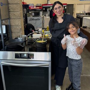 Chef Kimberly Ayala poses with her daughter demonstrating how safe induction cooking is with children at South Bay Appliance in Gardena, CA.
