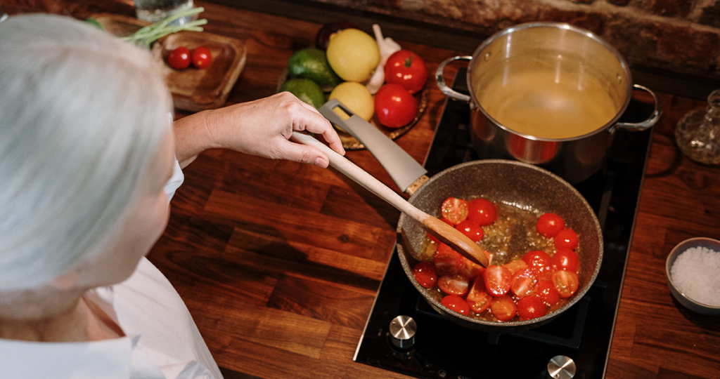 Person cooking tomato sauce for pasta on an induction cooktop